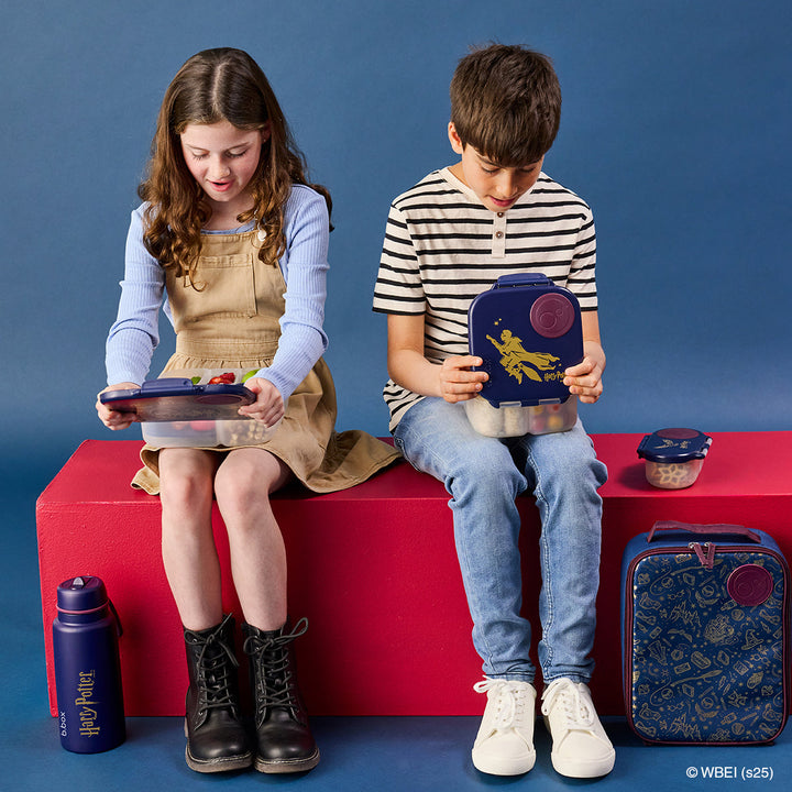 Children holding Harry Potter lunch boxes beside coordinating bags and bottles