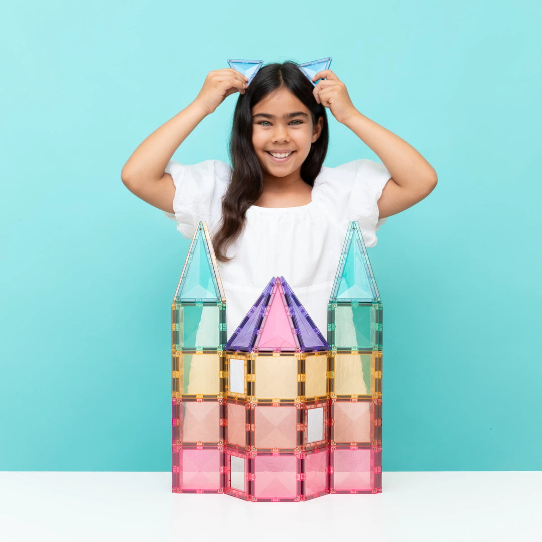 Child playing with a castle built from Connetix pastel magnetic tiles