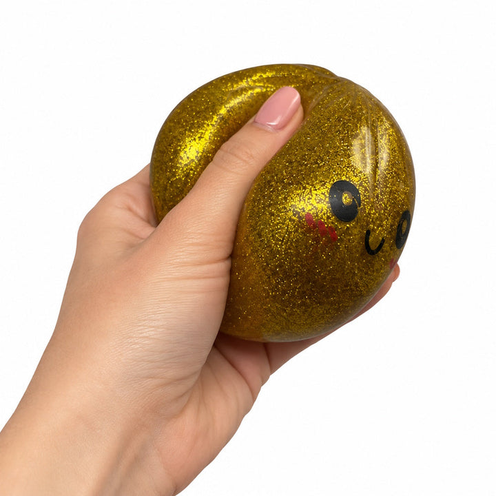 Golden glitter dumpling being gently squeezed by hand