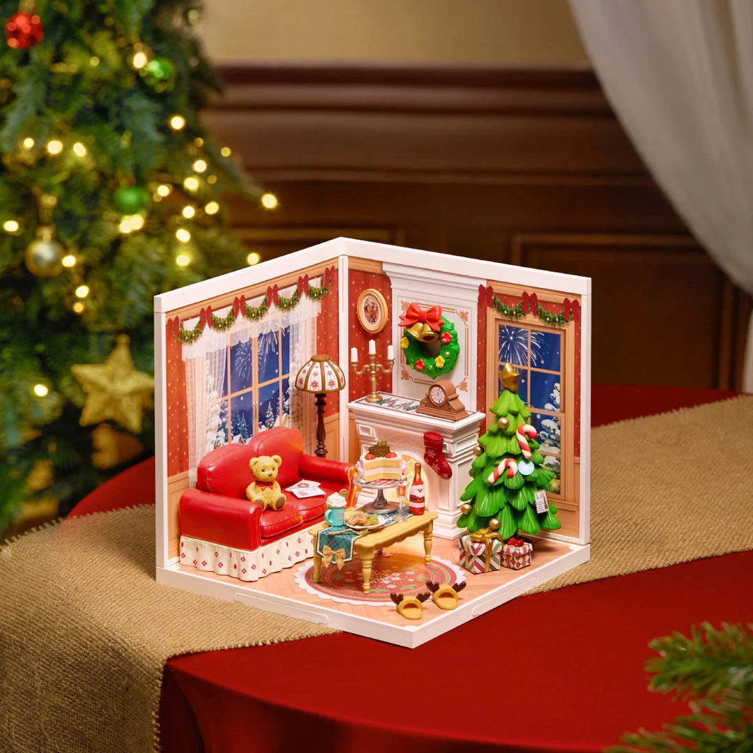 Rolife miniature Christmas living room diorama on a red table runner, showing red sofa, fireplace, Christmas tree and lit windows.